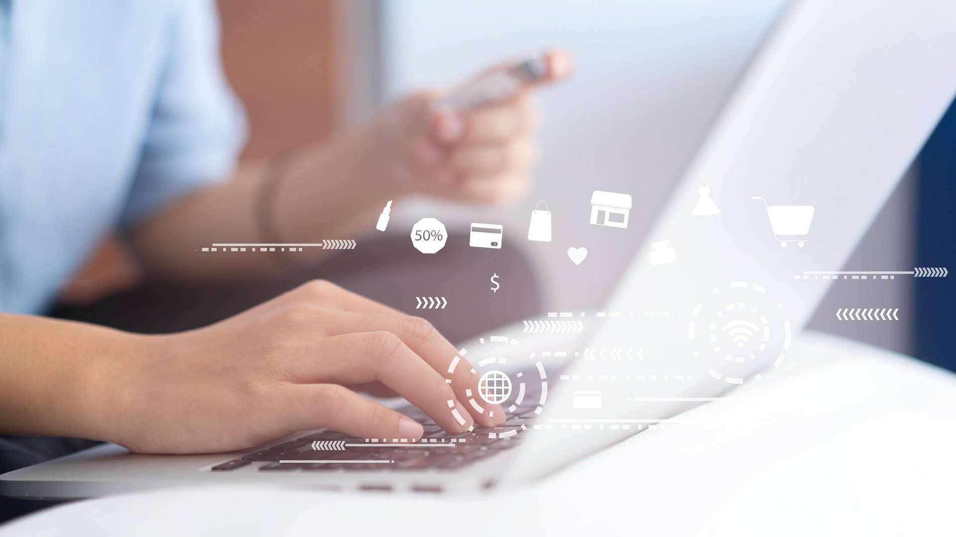 Hände tippen auf einer Laptop-Tastatur, während eine Person ein Smartphone hält. Schwebende Symbole und Icons, wie Einkaufswagen und Prozentsätze, verdeutlichen Online-Shopping in einem modernen, digitalen Umfeld.